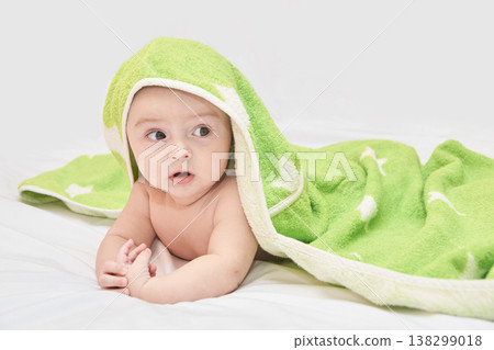 Adorable Caucasian Baby Wrapped In Green Blanket Looking Curious On A Soft White Bed 138299018