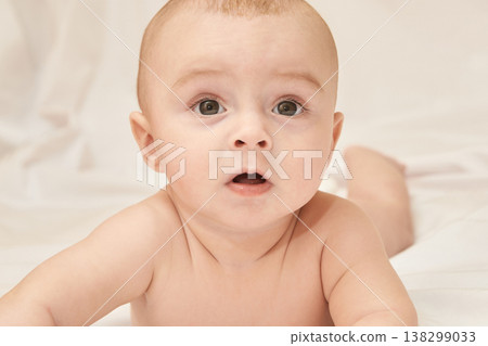 Cute Caucasian Baby Lying On White Blanket With Surprised Expression 138299033