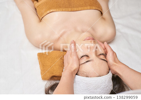 Relaxed Caucasian Female Enjoying Facial Massage In Spa With Calming Atmosphere Relaxed Caucasian Female Enjoying Facial Massage In Spa With Calming Atmosphere 138299059