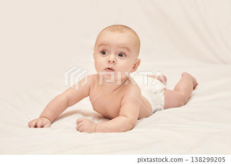 Caucasian Baby Lying On White Sheets With Curious Expression In Diaper Caucasian Baby Lying On White Sheets With Curious Expression In Diaper 138299205