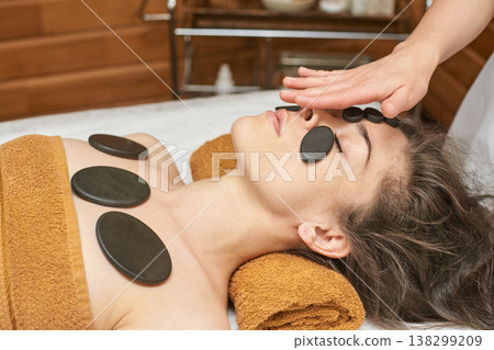 Young Caucasian Female Relaxing With Hot Stone Therapy In A Spa For Relaxation And Skin Young Caucasian Female Relaxing With Hot Stone Therapy In A Spa For Relaxation And Skin 138299209