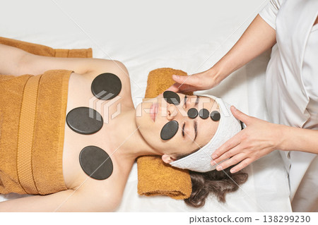 Young Caucasian Woman Relaxing With Hot Stone Therapy At Spa For Rejuvenation And Stress Relief Young Caucasian Woman Relaxing With Hot Stone Therapy At Spa For Rejuvenation And Stress Relief 138299230