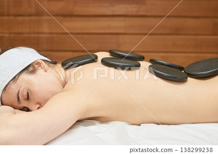 Relaxed Caucasian Female Enjoying Hot Stone Massage For Stress Relief And Relaxation In Spa Setting Relaxed Caucasian Female Enjoying Hot Stone Massage For Stress Relief And Relaxation In Spa Setting 138299238
