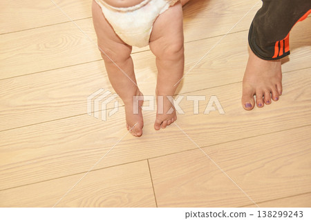 Baby Steps Caucasian Infant And Adult Feet On Wooden Floor With Diaper Baby Steps Caucasian Infant And Adult Feet On Wooden Floor With Diaper 138299243