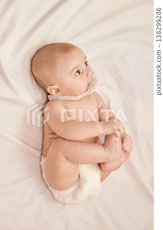 Caucasian Baby Lying On Soft White Blanket Holding Foot With Pacifier In Mouth Caucasian Baby Lying On Soft White Blanket Holding Foot With Pacifier In Mouth 138299286