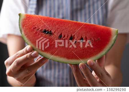Close-up of woman's hands holding sliced fresh watermelon, healthy tropical fruit for summer season Close-up of woman's hands holding sliced fresh watermelon, healthy tropical fruit for summer season 138299298