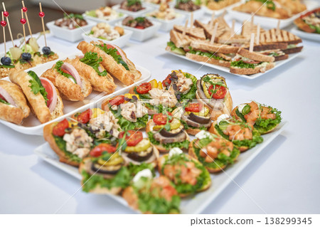Assorted appetizers and sandwiches on a white table for elegant party catering Assorted appetizers and sandwiches on a white table for elegant party catering 138299345