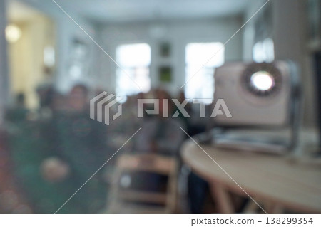 Blurred group of adults in a room with projector and unfocused background 138299354