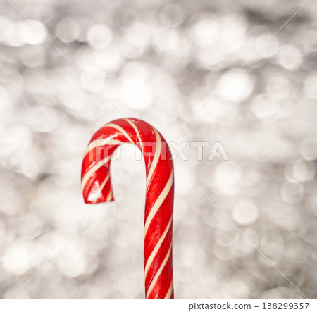 Festive red candy cane with white stripes on sparkling silver bokeh background for christmas 138299357