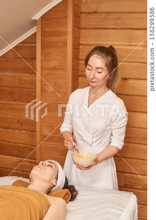 Spa Treatment Session With Professional Attendant In Relaxing Wooden Interior 138299386