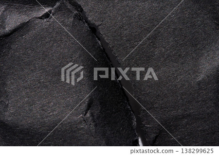 Close-up of torn dark paper texture with visible fiber details creating a dramatic abstract surface Close-up of torn dark paper texture with visible fiber details creating a dramatic abstract surface 138299625