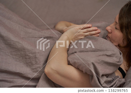Relaxed caucasian adult female lying peacefully on bed with hands in meditation pose Relaxed caucasian adult female lying peacefully on bed with hands in meditation pose 138299765