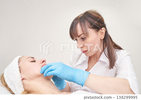 Female beautician performing facial treatment on young caucasian woman in spa clinic setting Female beautician performing facial treatment on young caucasian woman in spa clinic setting 138299995