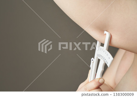 Female caucasian adult measuring arm fat with caliper for health and fitness assessment Female caucasian adult measuring arm fat with caliper for health and fitness assessment 138300009