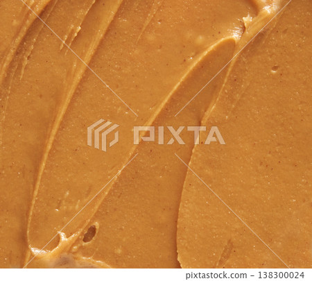 Close-Up Of Creamy Smooth Peanut Butter Texture With Swirls For Delicious Spread And Snack Ideas Close-Up Of Creamy Smooth Peanut Butter Texture With Swirls For Delicious Spread And Snack Ideas 138300024