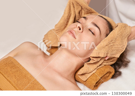 Young Caucasian Female Relaxing During Spa Treatment With Towels At Wellness Center Young Caucasian Female Relaxing During Spa Treatment With Towels At Wellness Center 138300049