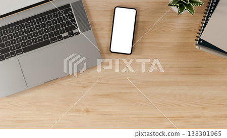 Top view close up of white screen smartphone with laptop and books aside pot plant on wooden table. Top view close up of white screen smartphone with laptop and books aside pot plant on wooden table. 138301965