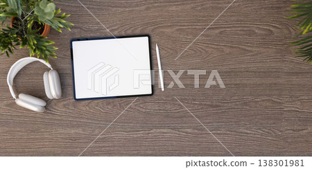 Top view of white screen tablet with stylus pencil and headphones aside potted plant on wooden table Top view of white screen tablet with stylus pencil and headphones aside potted plant on wooden table 138301981