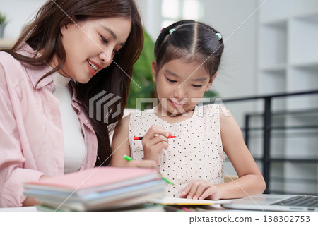 Mother assisting daughter with homework at home Mother assisting daughter with homework at home 138302753