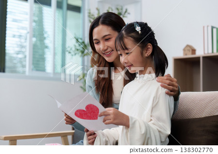 Mother and daughter sharing a heartfelt moment with a card 138302770