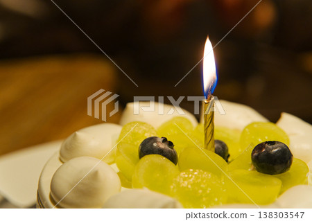 Single Lit Candle on Grape Blueberry Cream Birthday Cake Close-Up Single Lit Candle on Grape Blueberry Cream Birthday Cake Close-Up 138303547
