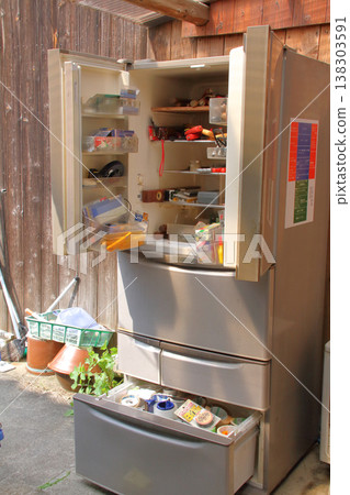 A broken refrigerator is being used as a storage unit for tools and other items. A broken refrigerator is being used as a storage unit for tools and other items. 138303591