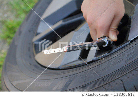 This image shows someone checking tire pressure using a pencil-type air gauge when changing to summer tires. This image shows someone checking tire pressure using a pencil-type air gauge when changing to summer tires. 138303612
