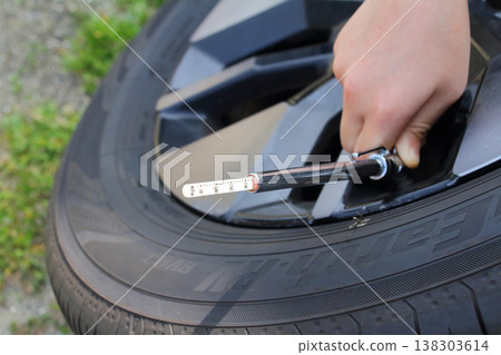This image shows someone checking tire pressure using a pencil-type air gauge when changing to summer tires. This image shows someone checking tire pressure using a pencil-type air gauge when changing to summer tires. 138303614