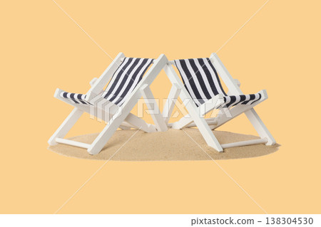 Two beach chairs with stripes sit on sand under summer sun Two beach chairs with stripes sit on sand under summer sun 138304530