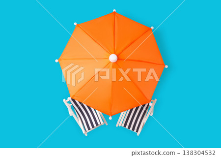 Orange umbrella and striped chairs sit on blue space 138304532