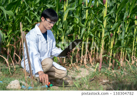 Asian agricultural researcher man holding clipboard checking water supply while sitting in crop farm 138304782