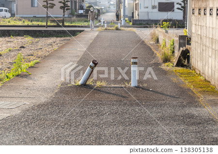 A scene of a narrow alley with a tilted bollard. 138305138