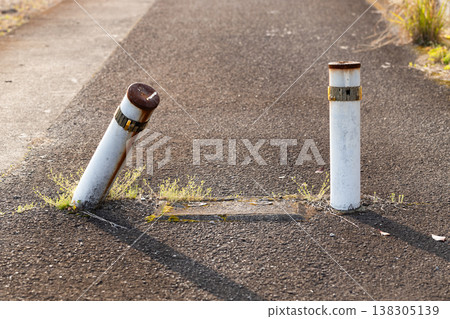 A scene of a narrow alley with a tilted bollard. 138305139