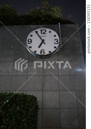 A clock illuminated in the night city 138305151