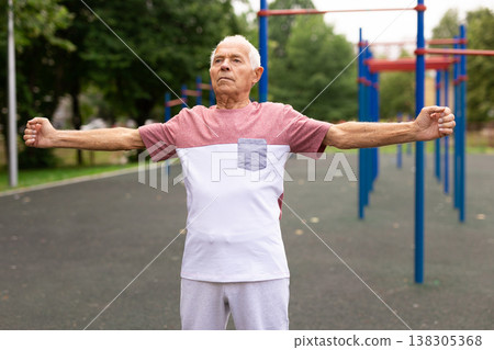 Elderly man doing fitness exercises outdoors 138305368