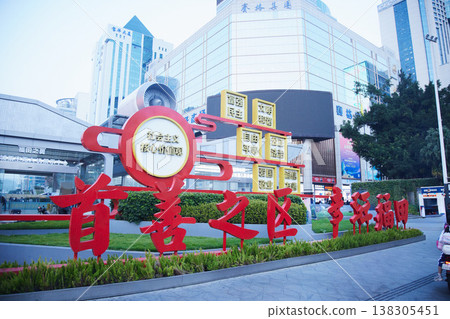 A monument of "Socialist Core Values" and a cluster of modern buildings in the city center of Futian District, Shenzhen, China. A monument of "Socialist Core Values" and a cluster of modern buildings in the city center of Futian District, Shenzhen, China. 138305451