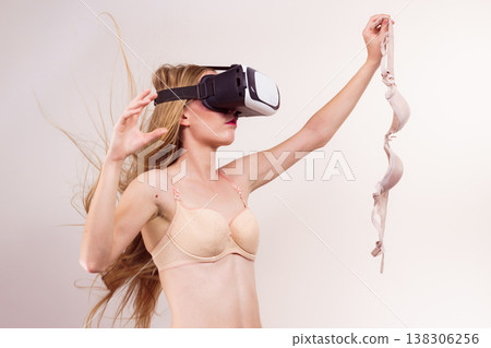 Girl in virtual reality goggles holds bra 138306256