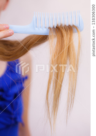 Blonde woman with her damaged dry hair. 138306300