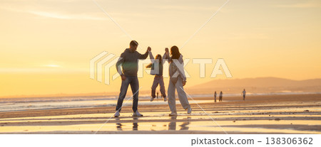 Child jumping between parents on beach at sunset Child jumping between parents on beach at sunset 138306362