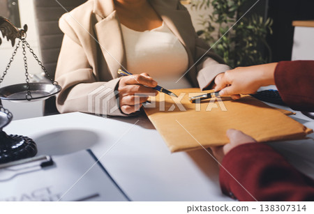 Judge gavel with Justice lawyers having team meeting at law firm in background. Notary with client in office Judge gavel with Justice lawyers having team meeting at law firm in background. Notary with client in office 138307314