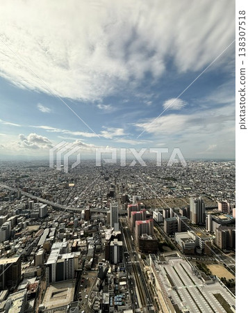 Osaka: A vast cityscape and blue sky viewed from an observation deck. Osaka: A vast cityscape and blue sky viewed from an observation deck. 138307518