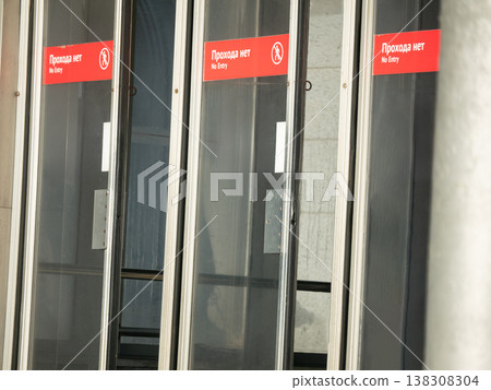 Glass doors with no entry sign at building entrance. Red warning label on transparent door frame indicating restricted area. Prohibition safety signal for public access control concept. 138308304