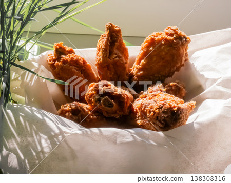 Crispy fried chicken wings in paper basket. Appetizing fast food snack served in container. Hot greasy roasted poultry pieces for lunch or dinner menu. Fresh crunchy snack concept. 138308316