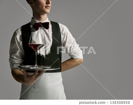 Close up of waiter torso holding tray with wine glass against neutral background. 138308938