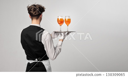 Waiter seen from back holding tray with cocktails in studio environment. Waiter seen from back holding tray with cocktails in studio environment. 138309065