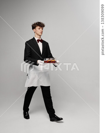Full body waiter walking with tray of cocktails in minimal studio environment. Full body waiter walking with tray of cocktails in minimal studio environment. 138309099