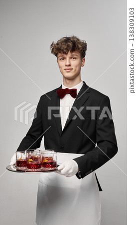 Waiter serving tray with multiple red cocktails in glasses in clean studio setup. Waiter serving tray with multiple red cocktails in glasses in clean studio setup. 138309103