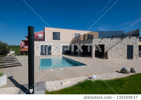 Modular modern smart house with outdoor pool, stone facade and unfinished terrace showing automated features and work in progress 138309637