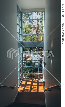 Modern interior staircase with large window and natural sunlight shadows, Minimal architecture corridor with glass wall and garden view in bright space Modern interior staircase with large window and natural sunlight shadows, Minimal architecture corridor with glass wall and garden view in bright space 138310771