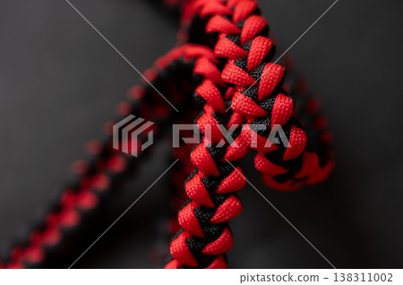 A strap woven in red and black against a black background. A strap woven in red and black against a black background. 138311002